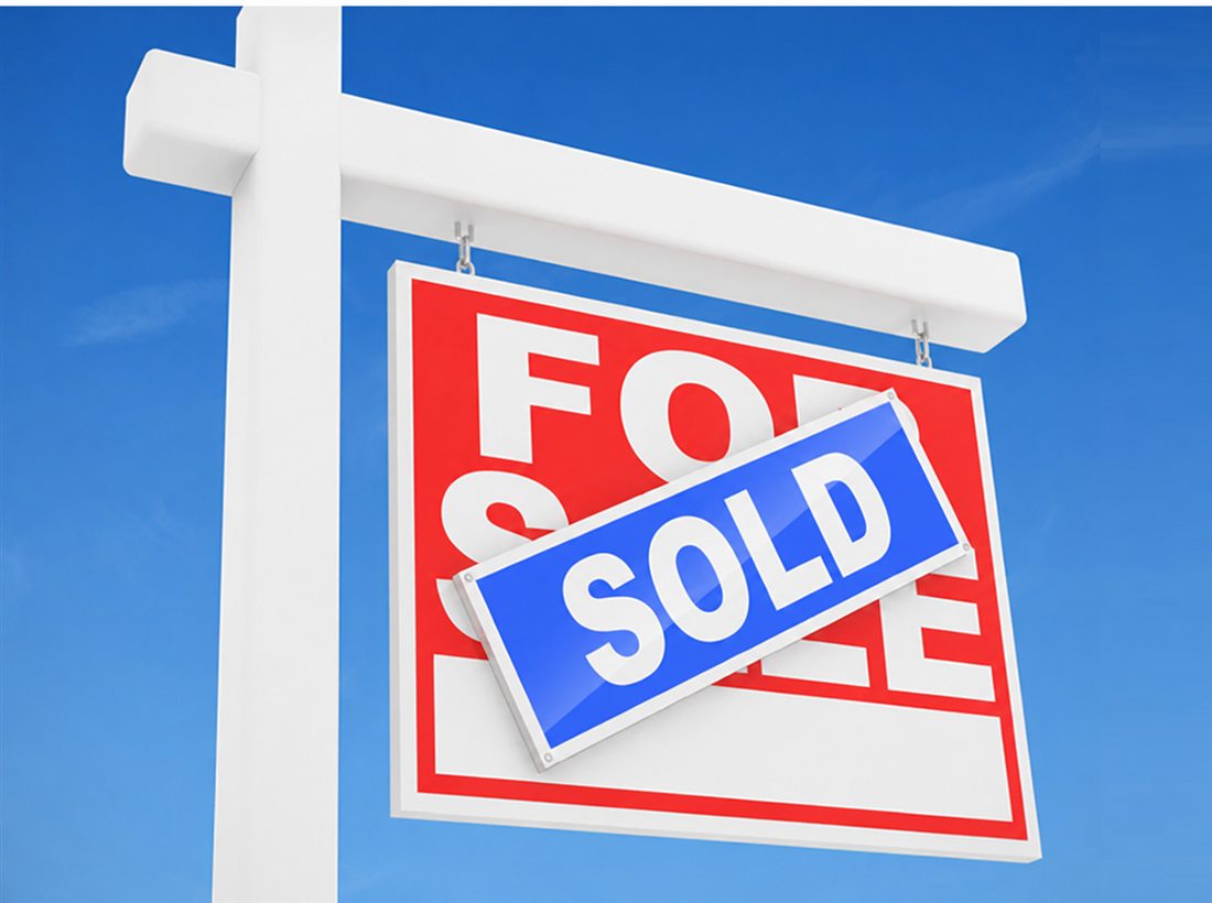 A for sale sign marked sold against a blue sky